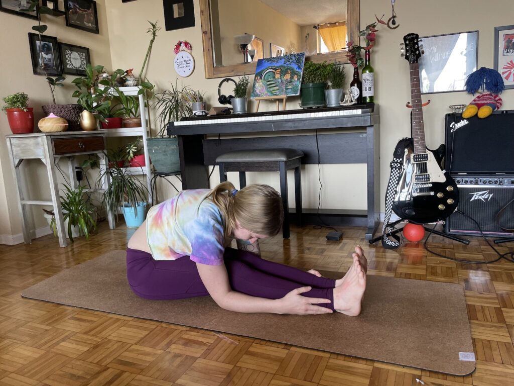 girl doing seated forward fold pose during yoga